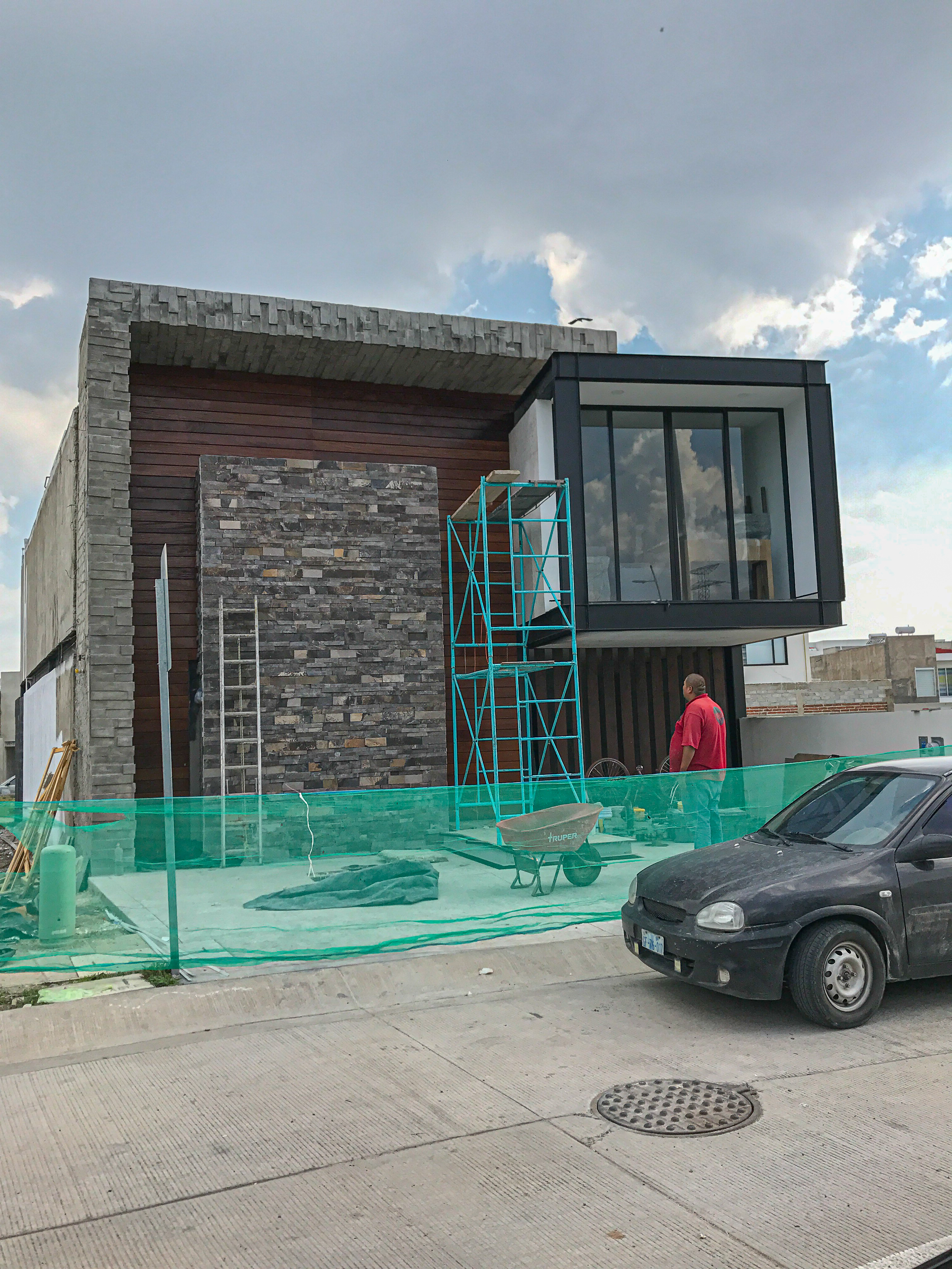 Fachada exterior de Casa MG con acabado de concreto aparente y acceso vehicular con porton, construcción residencial Fer Et Ciment León